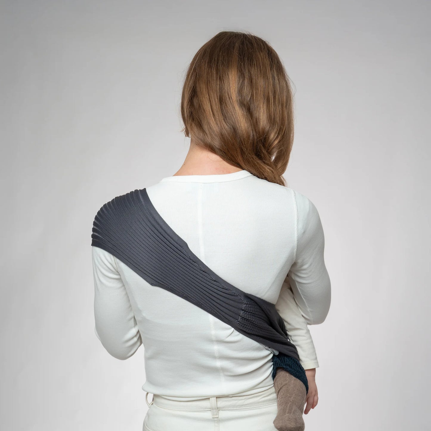 Rear view of a mother wearing a Coshen 3D knit baby carrier in anthracite, highlighting the ergonomic shoulder strap and wide back support for weight distribution.
