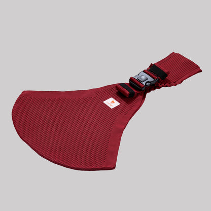 Angled perspective view of the cherry red Coshen carrier, highlighting the breathable 3D knit technical textile and minimalist design for stylish parents.