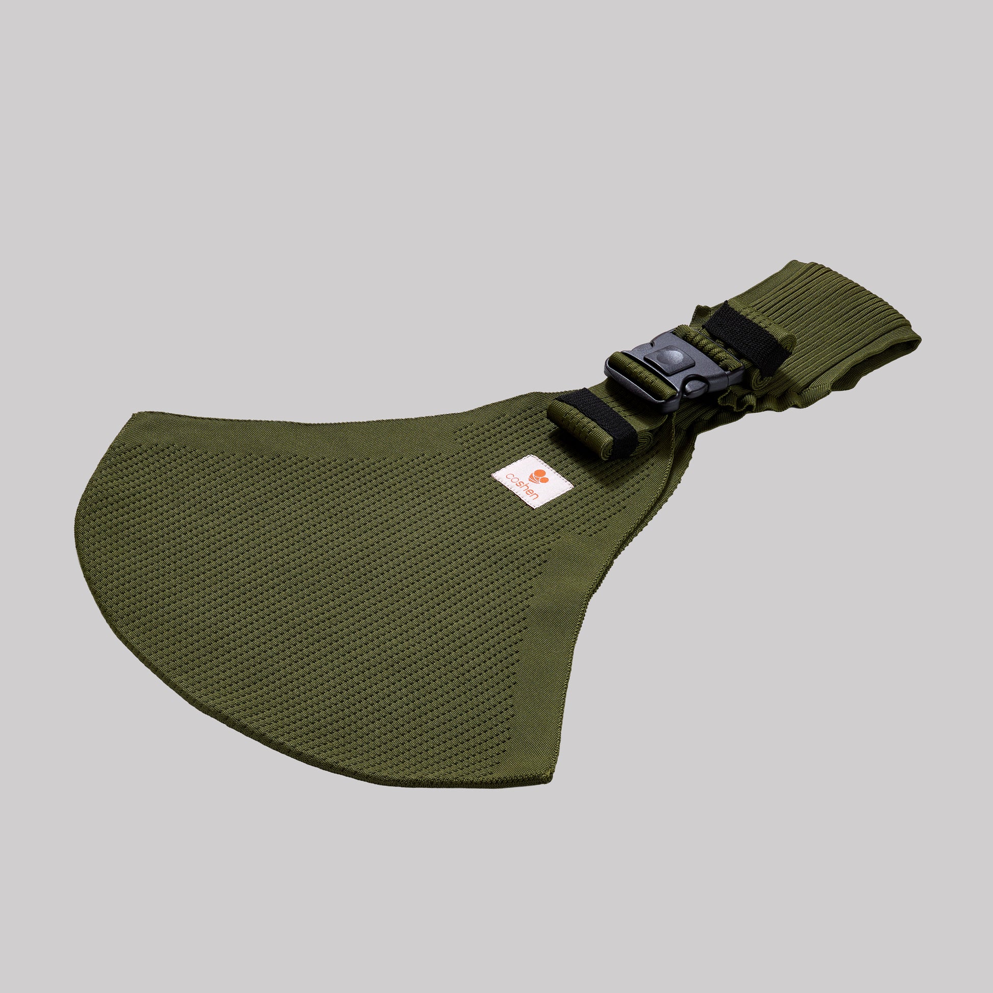 Angled perspective view of the green Coshen carrier, highlighting the breathable 3D knit technical textile and minimalist design for nature-conscious parents.