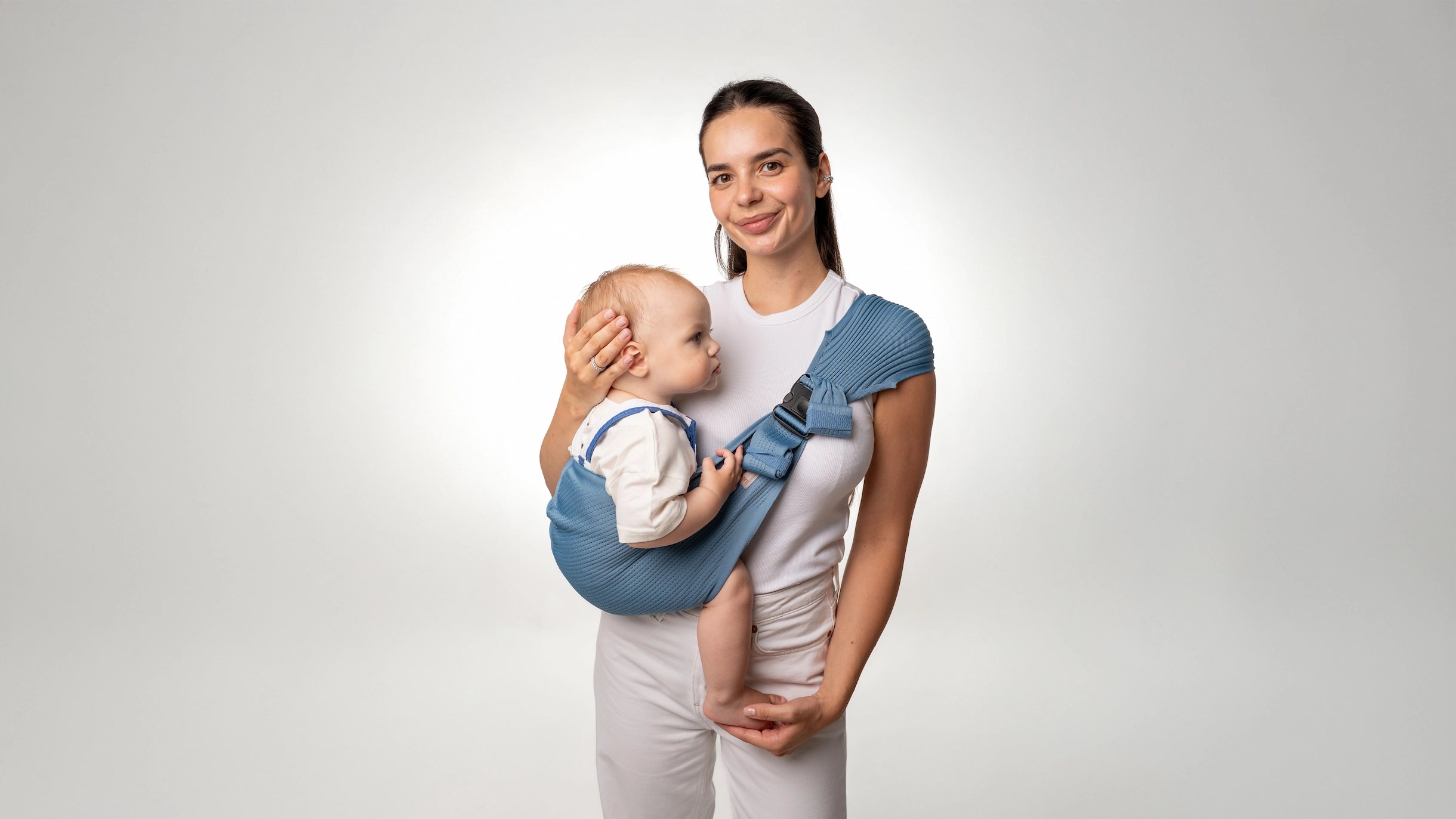 Mother wearing a toddler in a blue Coshen 3D knit seamless toddler carrier, showcase of ergonomic design on a white background.