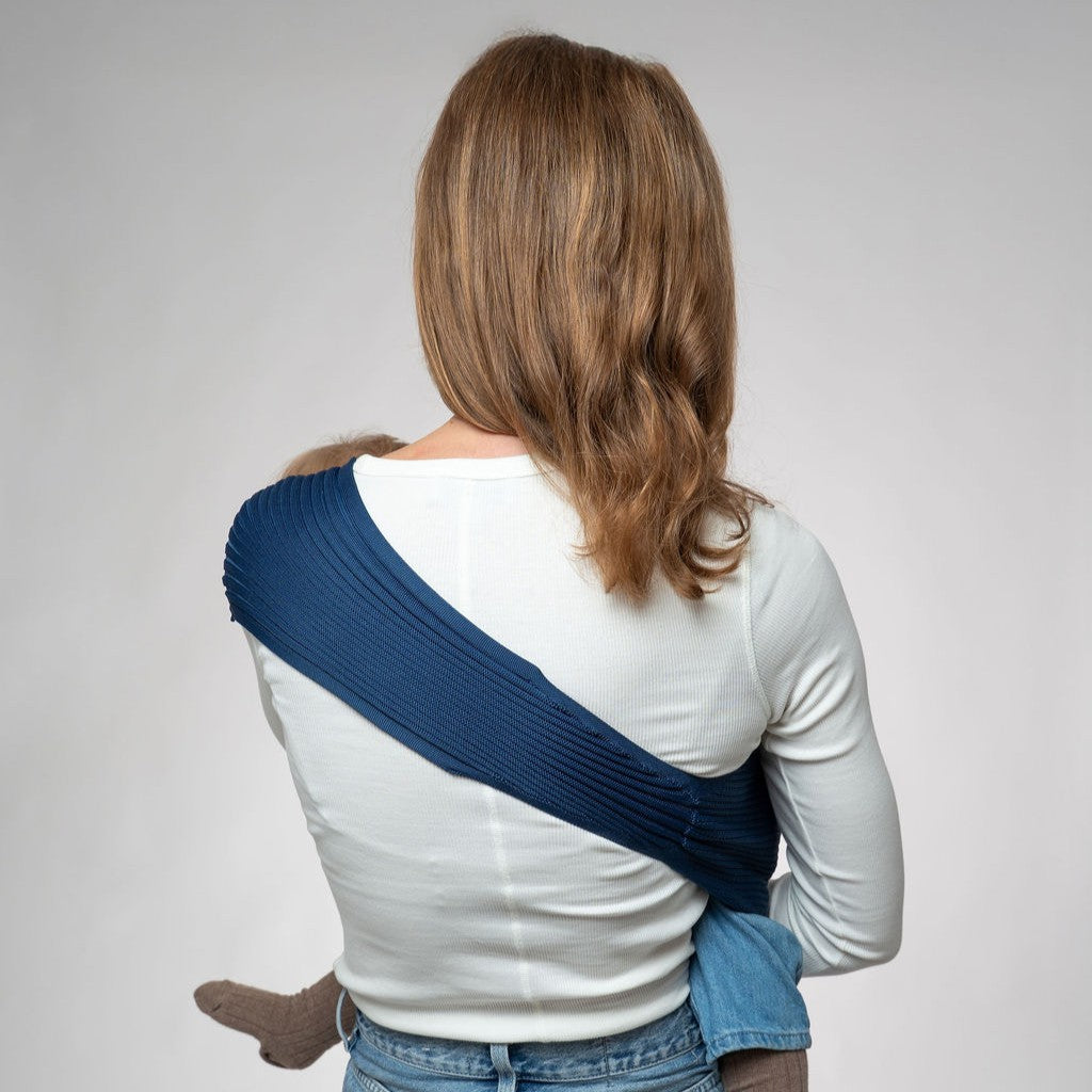 Coshen navy blue seamless knit toddler hip carrier being worn with white shirt and jeans.