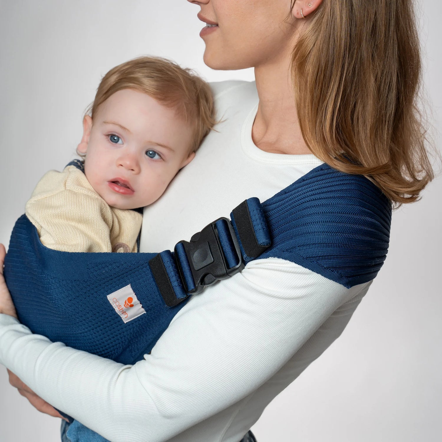 Primer plano de la hebilla de seguridad y el sistema de ajuste en un portabebé Coshen azul marino, garantizando un porteo seguro.